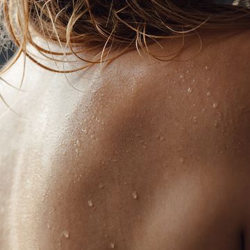 young european woman in shower close up back with water drops