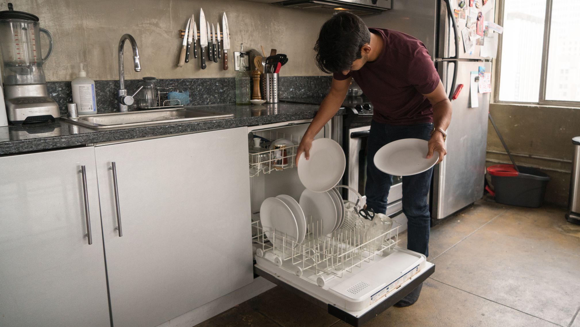 Young father putting dishes away