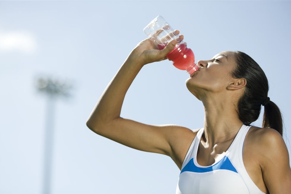 young female athlete drinking sports drink, portrait