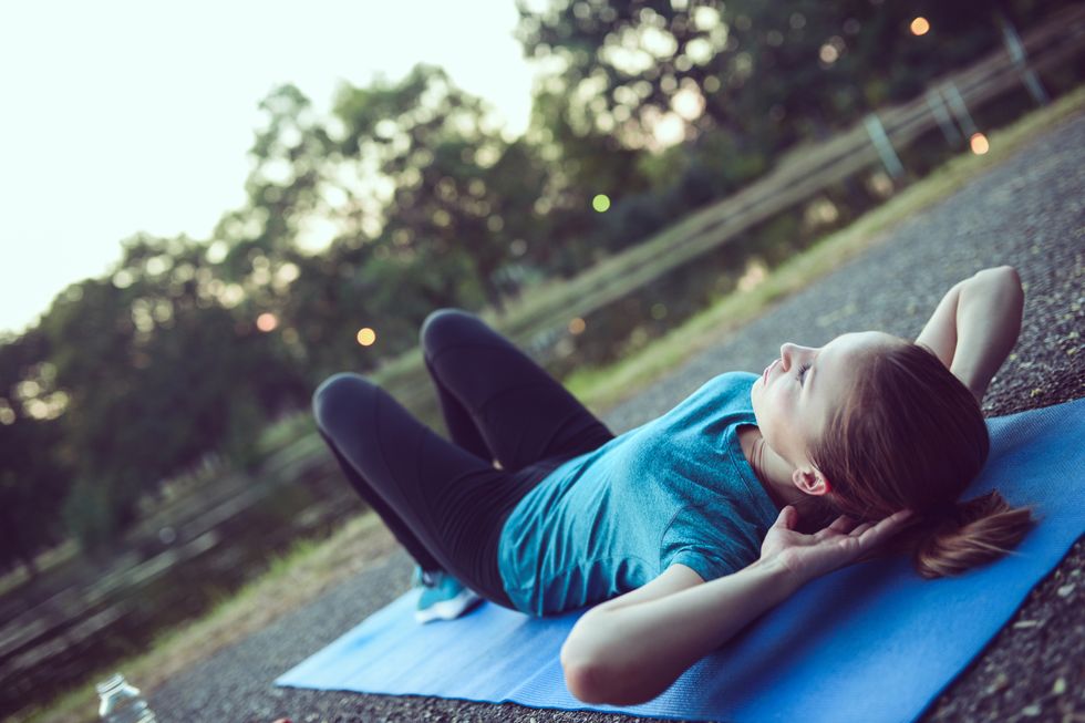 Young Female Athlete Performs Abs Crunches in City Park