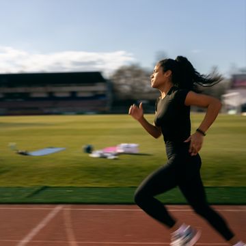 young female athlete running on racetrack