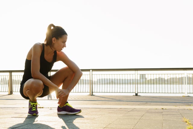 Young female jogger crouching and out of breath