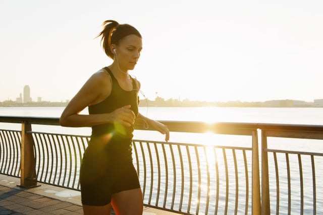 Young female jogger running at sunrise