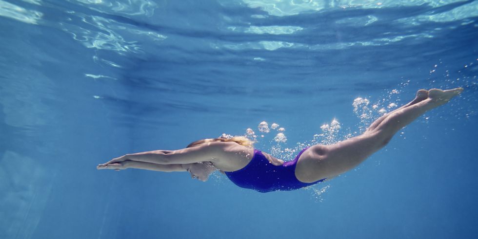 young female swimming underwater, side view