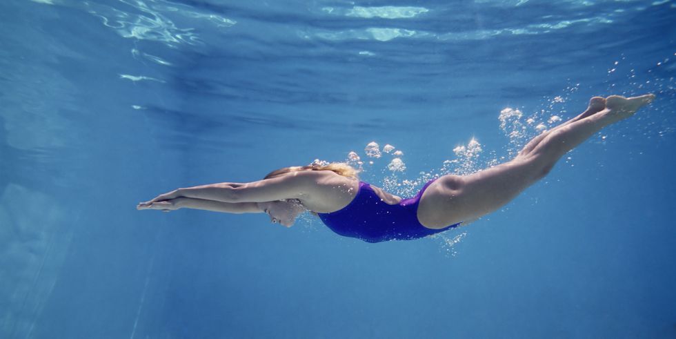 young female swimming underwater, side view
