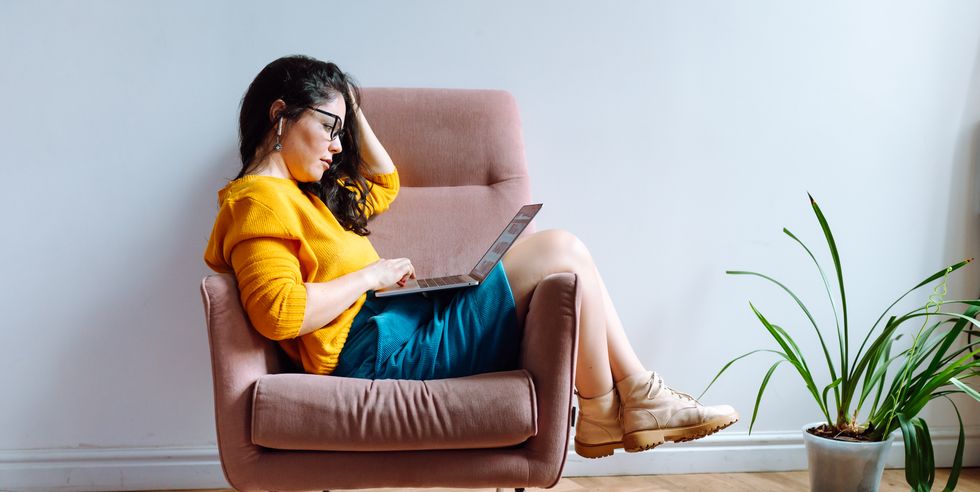 young female worker in casual outfit using laptop  for work in lounge room