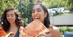 Young females hanging out in city eating pizza