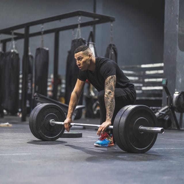 young fit hispanic man in the gym lifting heavy barbell deadlifts