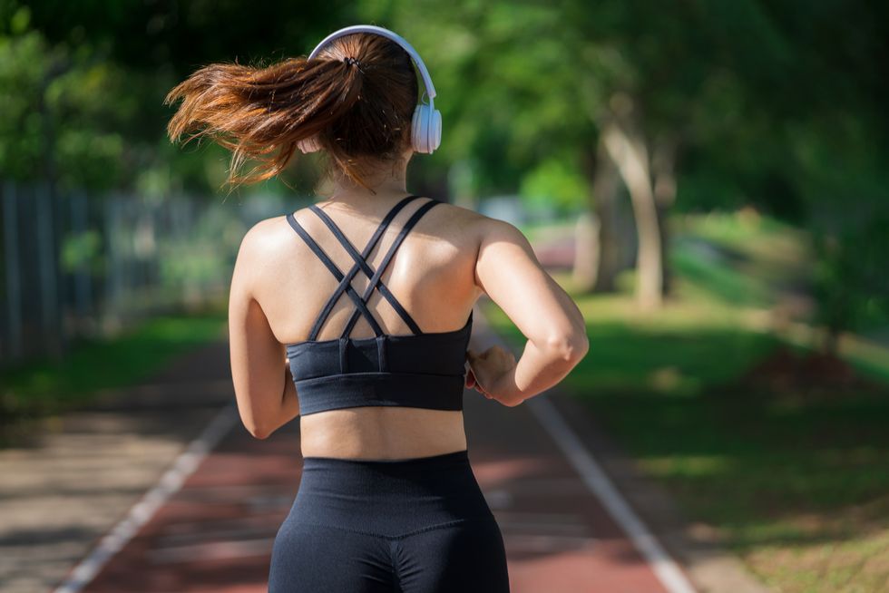 young fitness sports women runner running in the park happy athletic woman listening music on earphones while running in nature in the morning healthy fitness woman jogging outdoors