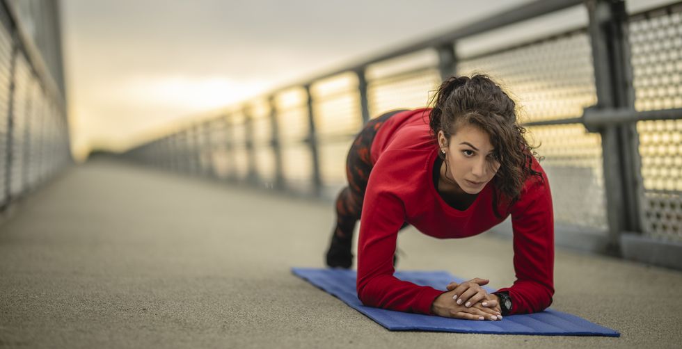 young fitness woman doing planking exercise outdoors