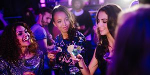 Young friends toasting with cocktails on night club party