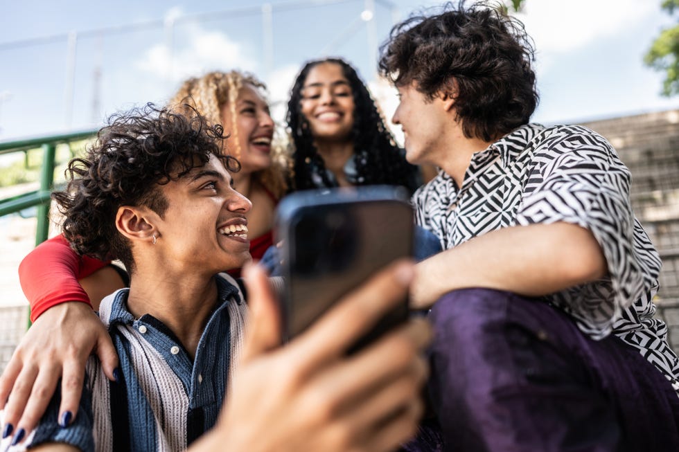 young friends using mobile phone outdoors