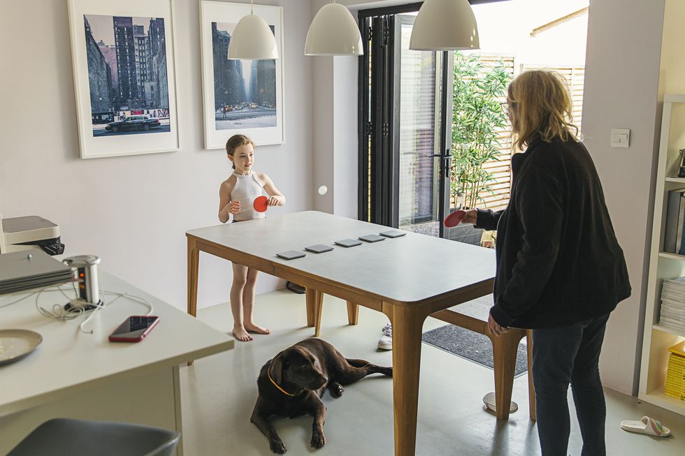 young girl and grandmother playing table tennis on dining table