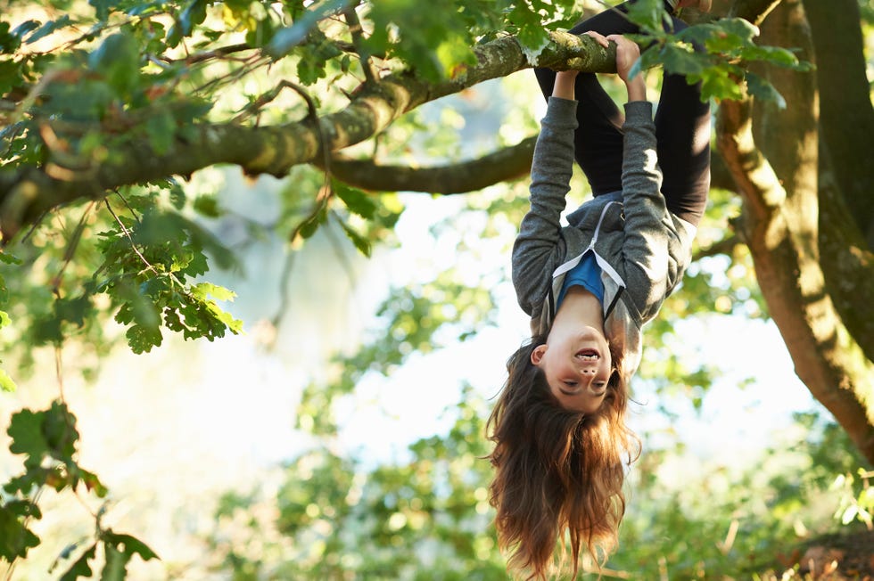 Young girl hanging upside down branch