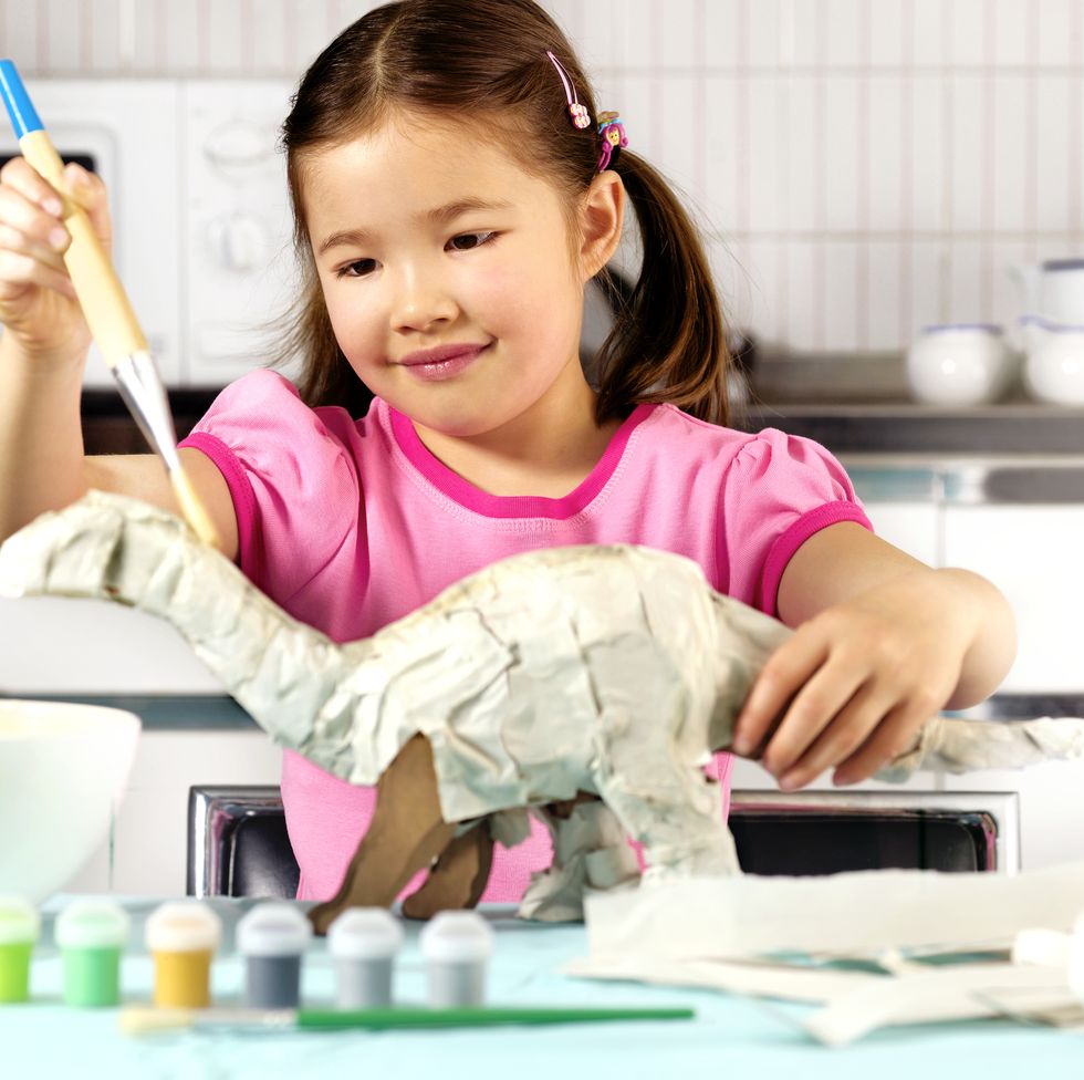 young girl in kitchen, making paper dinosaur, smiling fun activities for kids