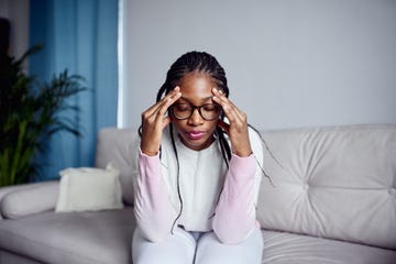 a young girl is sitting on the couch at home with her head in her hands