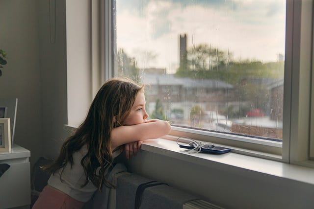 young girl looking out of window on a rainy day