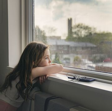 young girl looking out of window on a rainy day