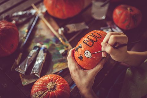 young girl painting on pumpkin in halloween
