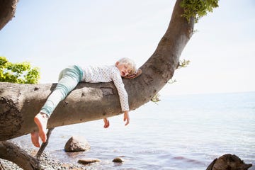 kind slapend op boomtak bij water