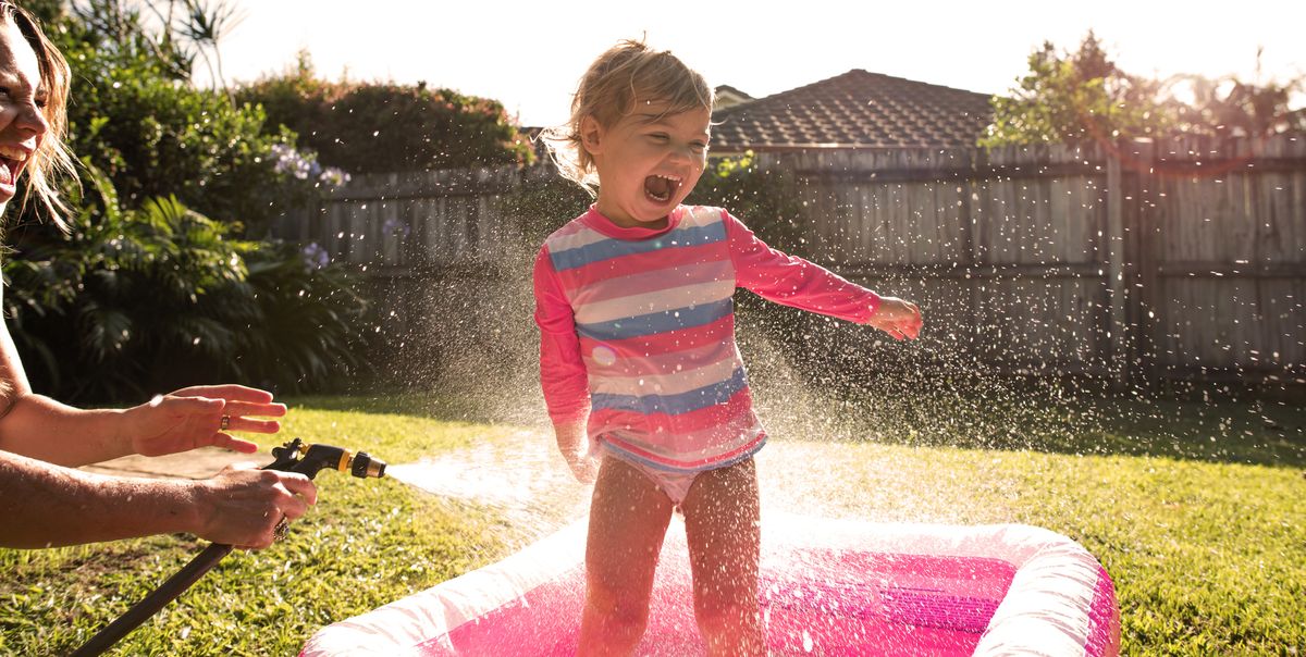 young girl splashing hose and pool and sunflare