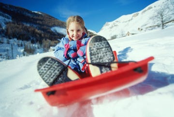 niña en trineo en la nieve