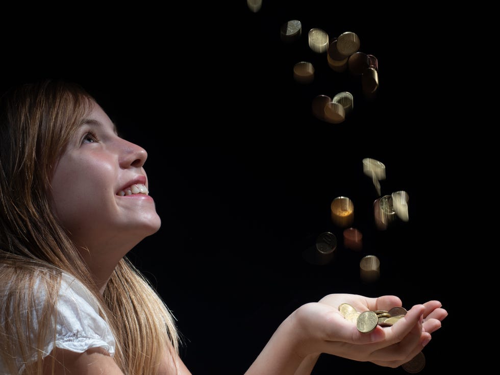 young girl with money falling from above