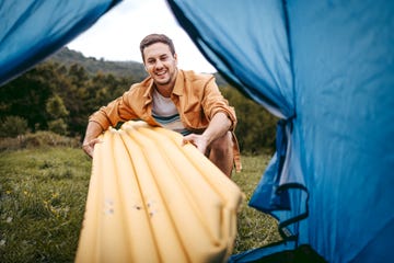 young handsome camper setting up his air bad for camping