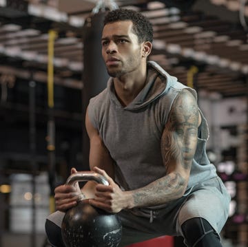 Young handsome mixed race Boxer Fighter training hard with a kettlebell in Gym Setting