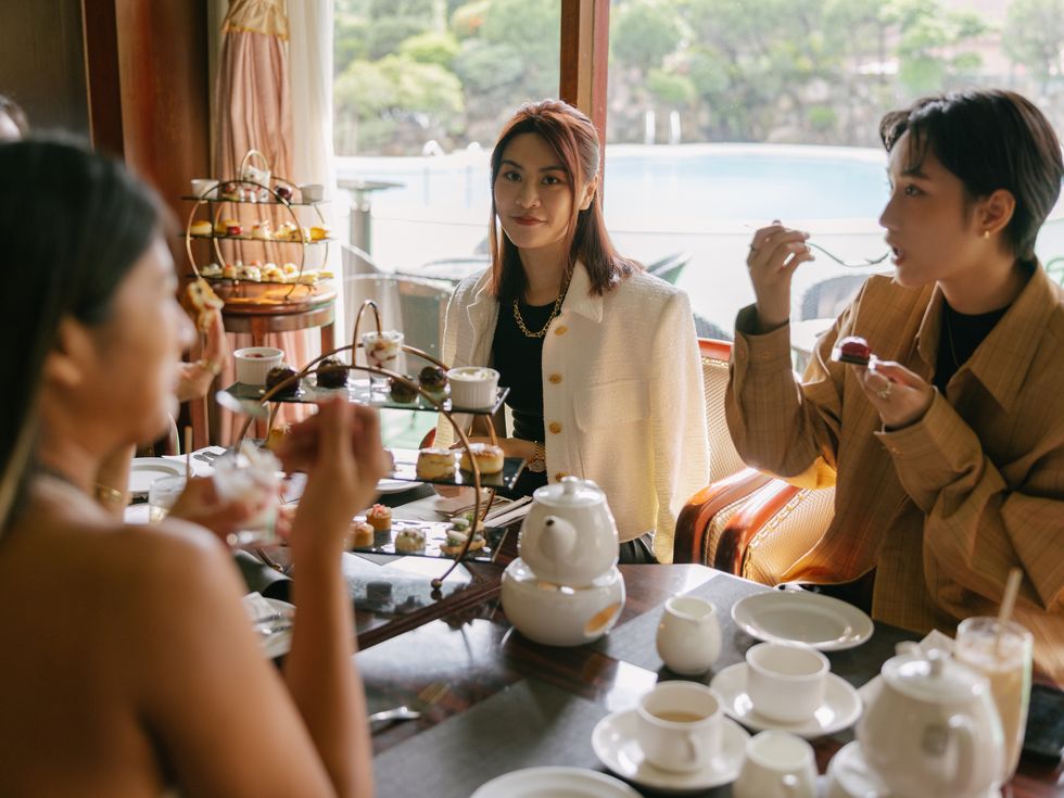 young happy asian women female friends eating cakes and dessert for afternoon tea in luxurious hotel or cafe indoors in daytime