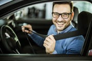 young happy man fastening his seatbelt before a trip by car
