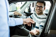 young happy man receiving new car keys in a showroom