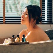 young happy woman enjoying essential oil bubble bath in bathroom with her eyes closed
