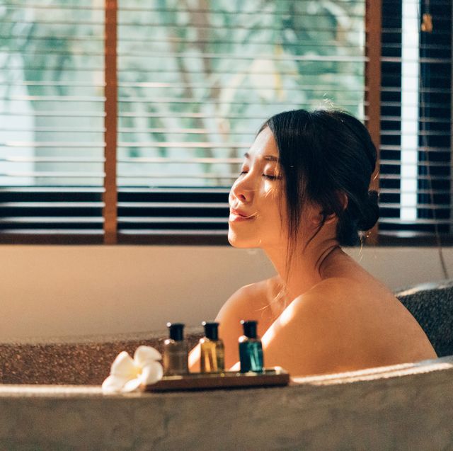 staycation young happy woman enjoying in bubble bath in hotel bathroom with her eyes closed