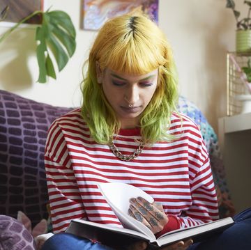 young hipster woman reading a book in her living room