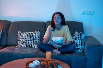 young hispanic female enjoys her evening at home she sits in her living room and watches tv