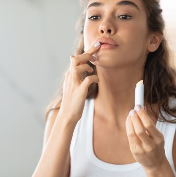 woman applying lip balm in bathroom