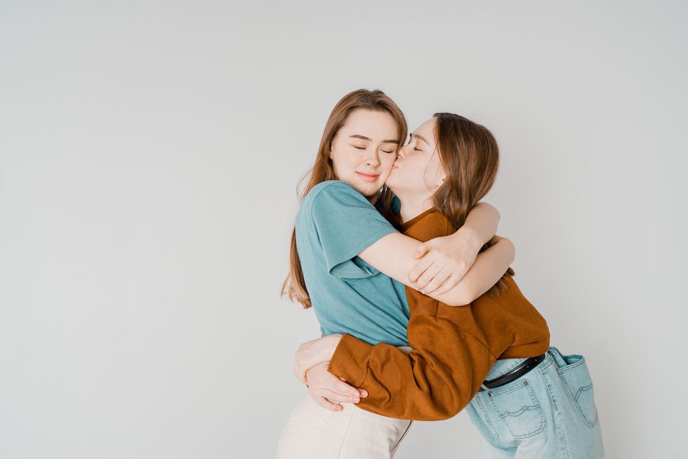 Young Lesbian Couple Embracing Against Gray Background