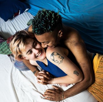 a young lgbt couple laughing and hugging in bed