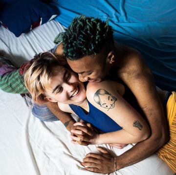 a young lgbt couple laughing and hugging in bed