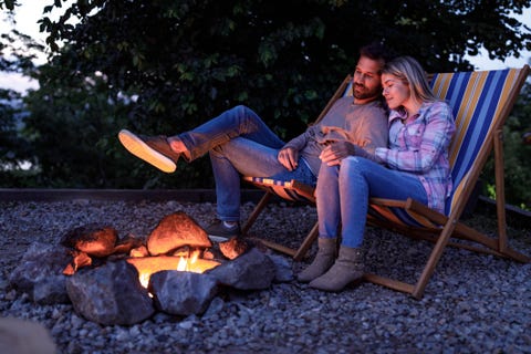 young loving couple relaxing in deck chairs by the bonfire