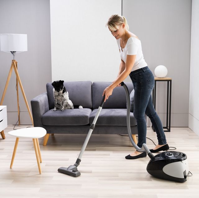 young maid cleaning carpet with vacuum cleaner