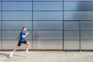 young male athlete running by silver wall