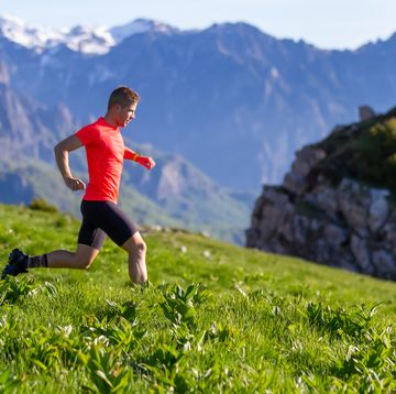 young male athlete trains running in the mountains at sunrise