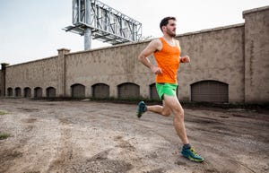 Young male runner running on urban wasteland