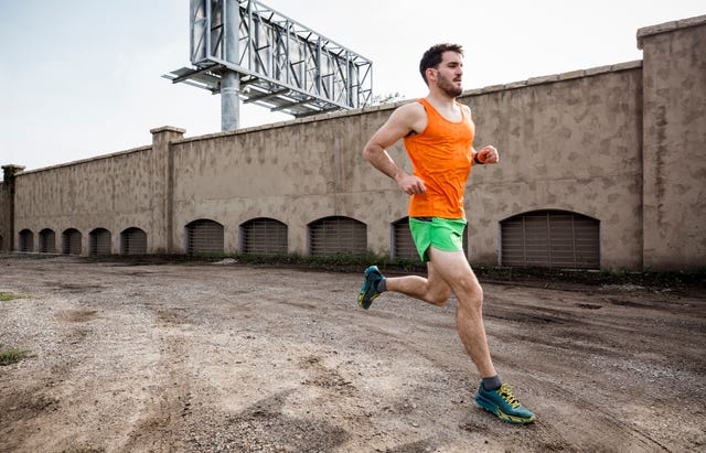 Young male runner running on urban wasteland