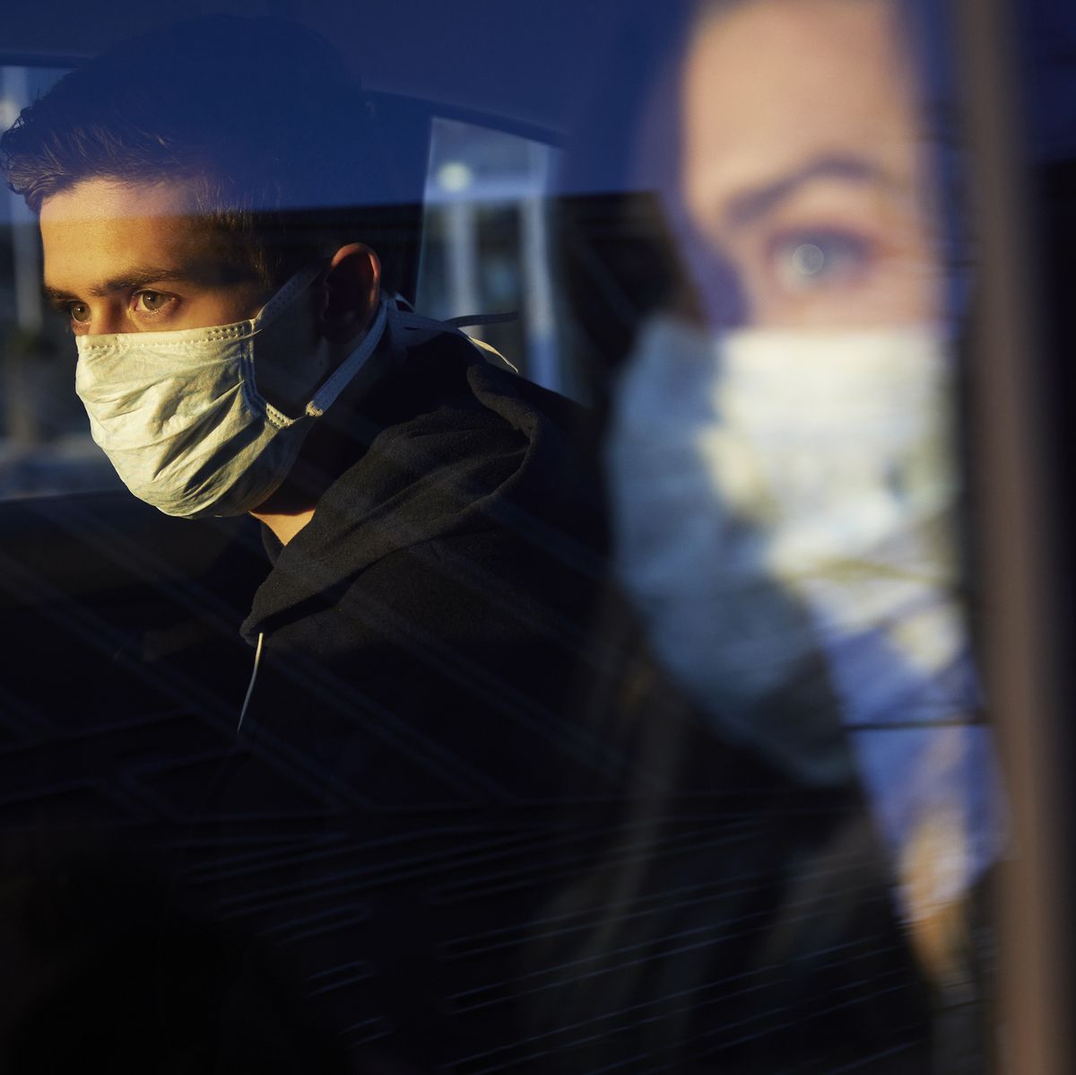 young man and woman in car wearing a virus protective face masks