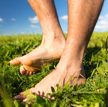 young man barefoot twisted feet on green grass