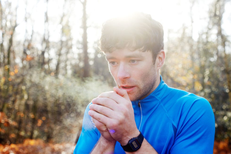 young man breathing on hands for warmth