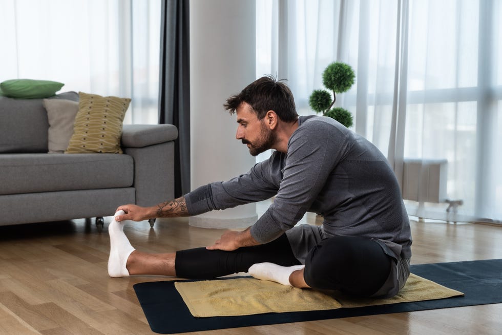 young man cancer survivor practicing home workout yoga training, stretching muscles and breathing exercise for healthy life after long struggle with sickness and pain warmup exercises for meditation